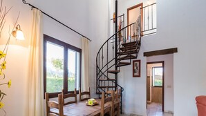 A dining area with a wooden table and chairs, a spiral staircase, and a view of greenery outside. - Outdoor Ibipozo Retreat With Pool (Pozo Alcon)