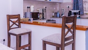Una cocina moderna con dos sillas de madera, una barra de bar de madera y lámparas colgantes.