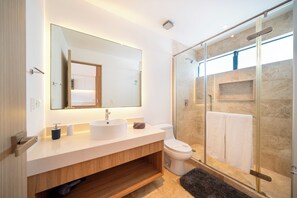 Ein modernes Badezimmer mit großem Spiegel, Waschbecken, Toilette und einer Duschkabine.
