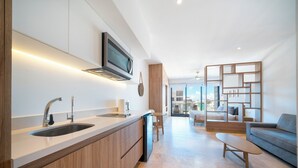A modern kitchen with a built-in dishwasher, a large sink, and a flat-screen TV mounted above the counter. - 1 Bedroom Pool & Gym - Piedra Azul 605 (Playa del Carmen)