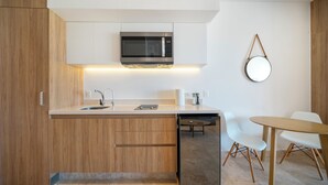 A modern kitchen with wooden cabinets, a built-in microwave, a dishwasher, and a round mirror on the wall. - 1 Bedroom Pool & Gym - Piedra Azul 605 (Playa del Carmen)