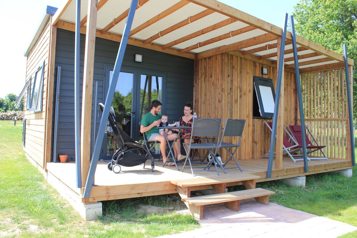 A wooden cabin with a covered porch, a table, and chairs.