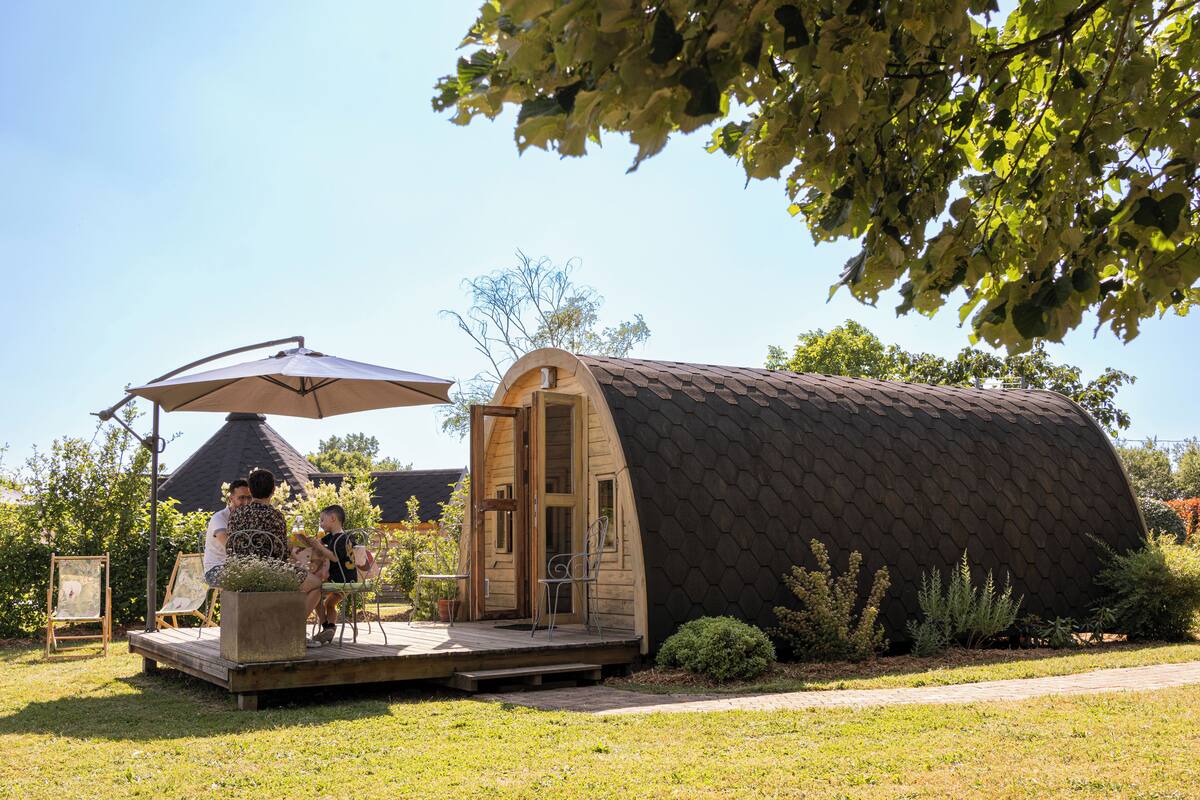 A small, wooden, dome-shaped structure with a door and a bench outside.