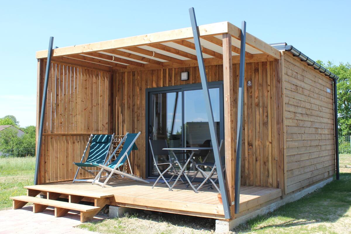 A wooden cabin with a porch, a table, and two chairs.