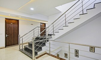 A modern staircase with metal railings and marble steps, leading to a wooden door labeled "207".