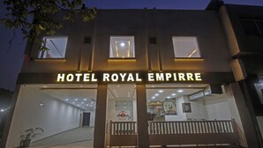 Exterior del Hotel Royal Empire con fachada moderna, señalización iluminada y un letrero de restaurante visible en el interior.
