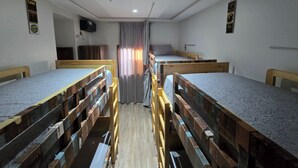 Ein Schlafsaalzimmer mit Etagenbetten, einem Schreibtisch, einem Stuhl und einem Fernseher.