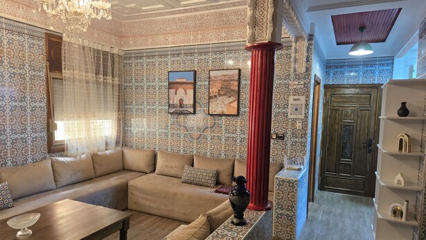 Ein Zimmer mit einem beigen Sofa, wandgestreiftem Wanddesign, einem Chandelier und einer Holztür.