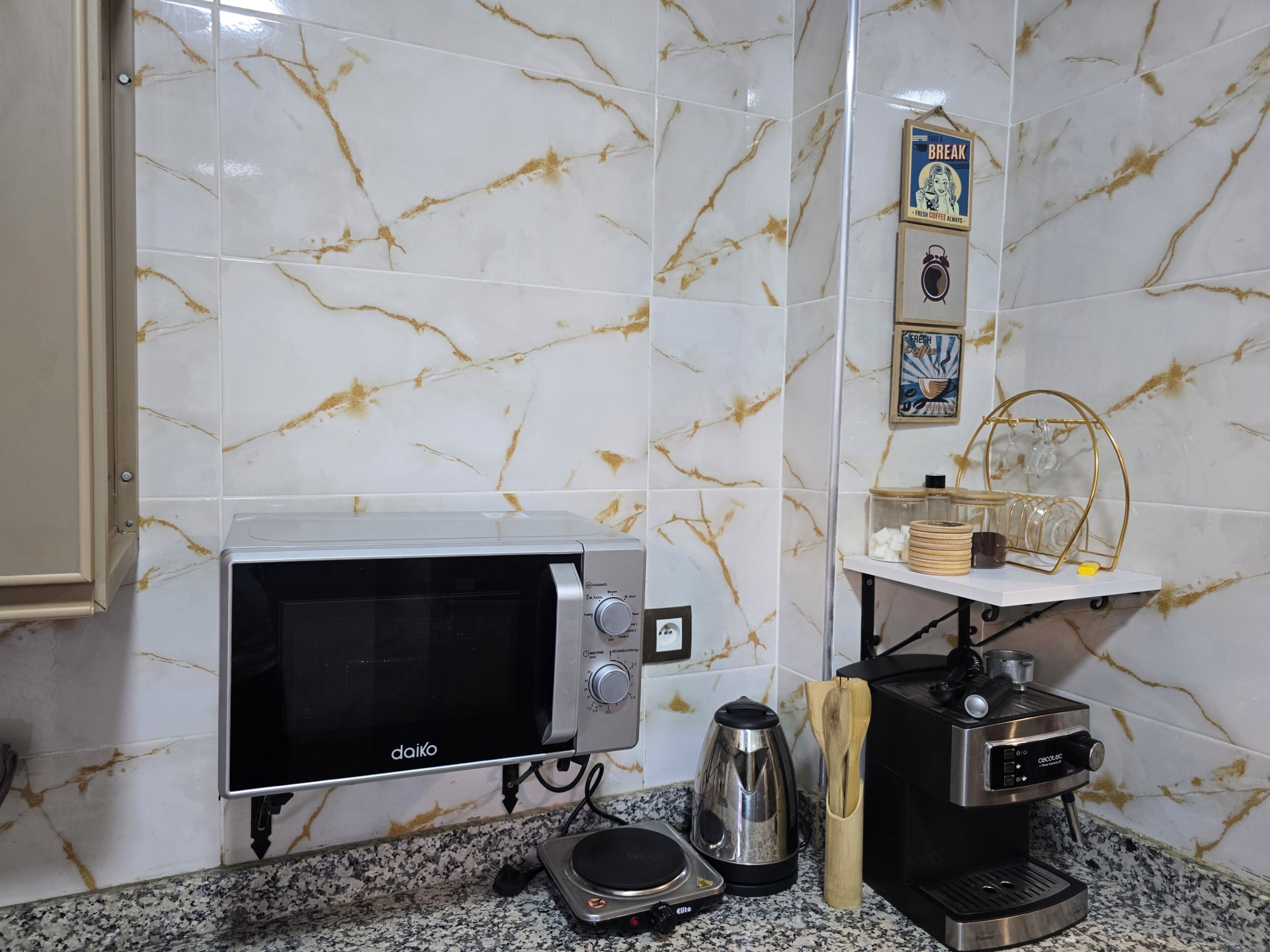 A kitchen with a microwave, coffee maker, and a kettle on the counter.