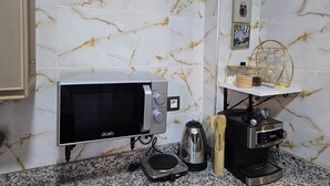 Eine Küche mit Mikrowelle, Kaffeemaschine und Wasserkocher auf der Arbeitsfläche.