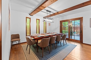 Un coin repas avec une table en bois, six chaises et un lustre.