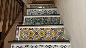 Una escalera con baldosas ornamentadas y estampadas que lleva a un rellano.