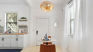 Una cocina moderna con armarios blancos, una mesa redonda con un florero y una lámpara colgante.
