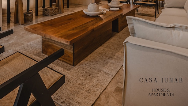 A modern living room with a wooden coffee table, white sofa, and a staircase with built-in lighting. - JUNAB HOUSE - HOUSE (The Cuyo)