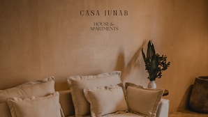 A living room with a wooden coffee table, a sofa with cushions, and a vase with flowers. - JUNAB HOUSE - HOUSE (The Cuyo)