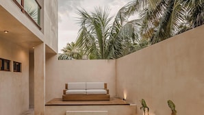 A modern outdoor pool area with a built-in bench and steps leading to a seating area, surrounded by a low wall and palm trees. - JUNAB HOUSE - HOUSE (The Cuyo)