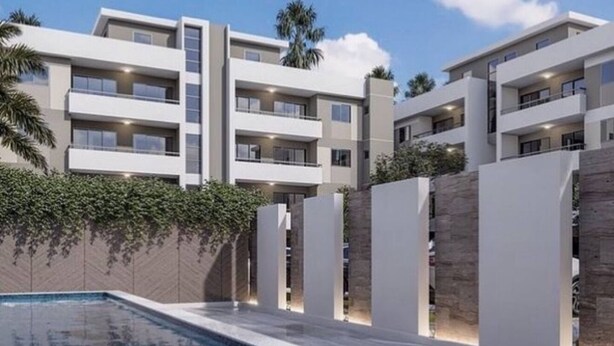 A modern multi-story hotel with a swimming pool, outdoor lighting, and a landscaped garden.