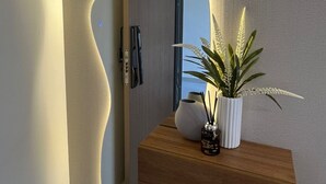 A modern interior with a wooden floating shelf holding a potted plant and a decorative item.