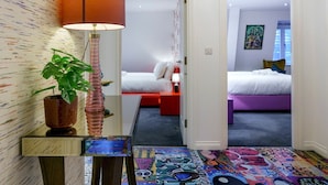 Habitación de hotel con diseño moderno, que incluye un espejo grande, una lámpara original y un suelo colorido.