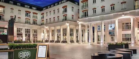 A hotel courtyard with a central seating area, columns, and a statue.