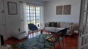 A living room with a sofa, chairs, a coffee table, and a large window with curtains.