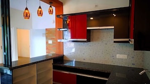 Una cocina moderna con encimera negra, armarios rojos y salpicadero con diseño.