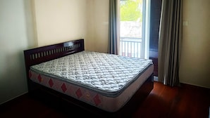 Una cama individual con un colchón estampado en una habitación con paredes lisas y una ventana con cortinas.