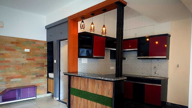 Una cocina moderna con una isla de madera, armarios rojos y salpicadero de azulejos.