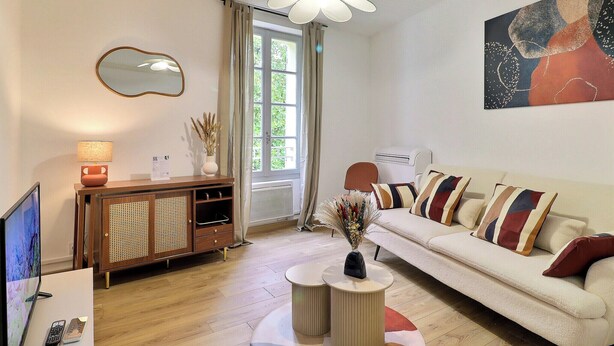 A modern living room with a sofa, a TV, a cabinet, and a ceiling light. - Nuit Étoilée - Cocoon in the Heart of Arles - A/C (Arles)