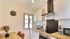 A compact kitchen with a wooden countertop, a built-in oven, a microwave, and a coffee machine. - Nuit Étoilée - Cocoon in the Heart of Arles - A/C (Arles)