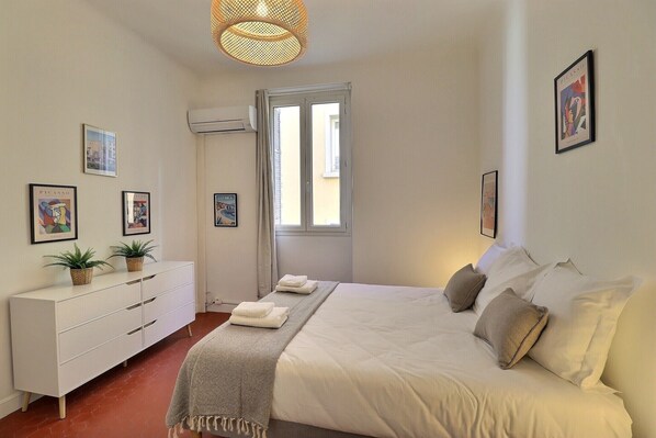 A bedroom with a bed, white dresser, potted plants, and artwork on the walls. - Casa Napoléon - Elegance in the City Center of Ajaccio (Ajaccio)