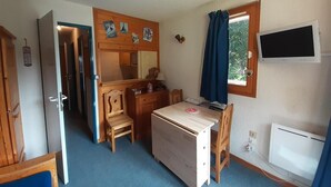 A compact room with a desk, chair, and a television.