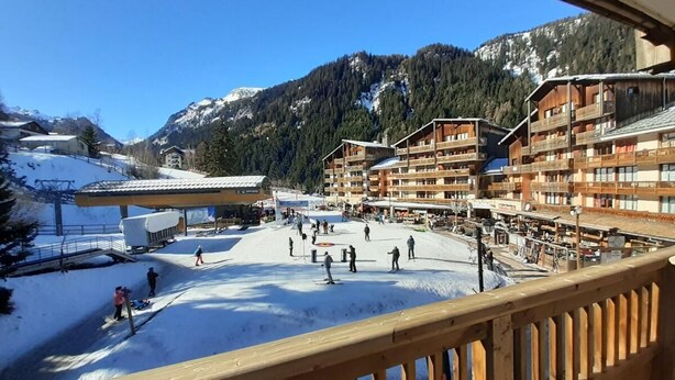 A ski resort with multiple buildings, a ski lift, and a snowy landscape.