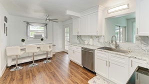 A modern kitchen with white cabinetry, a marble countertop, and a built-in dishwasher. - Siesta key paradise in Sarasota (Sarasota)