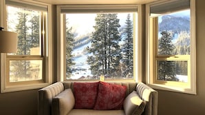 Eine Sitzecke mit Blick auf eine verschneite Landschaft durch drei Fenster.