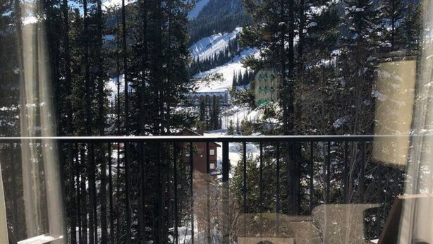 Ein Balkon mit Blick auf eine verschneite Berglandschaft und einen dichten Wald.