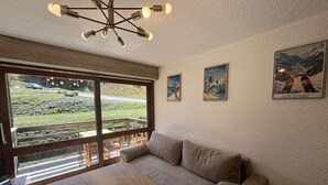 Tunnelmallinen huone, jossa on suuri ikkuna, puinen pöytä, sohva ja ainutlaatuinen kattovalaisin.