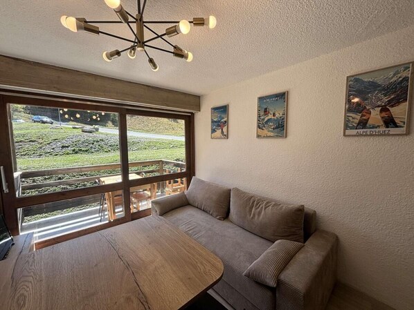 Une pièce chaleureuse avec une grande fenêtre, une table en bois, un canapé et un luminaire au plafond original.