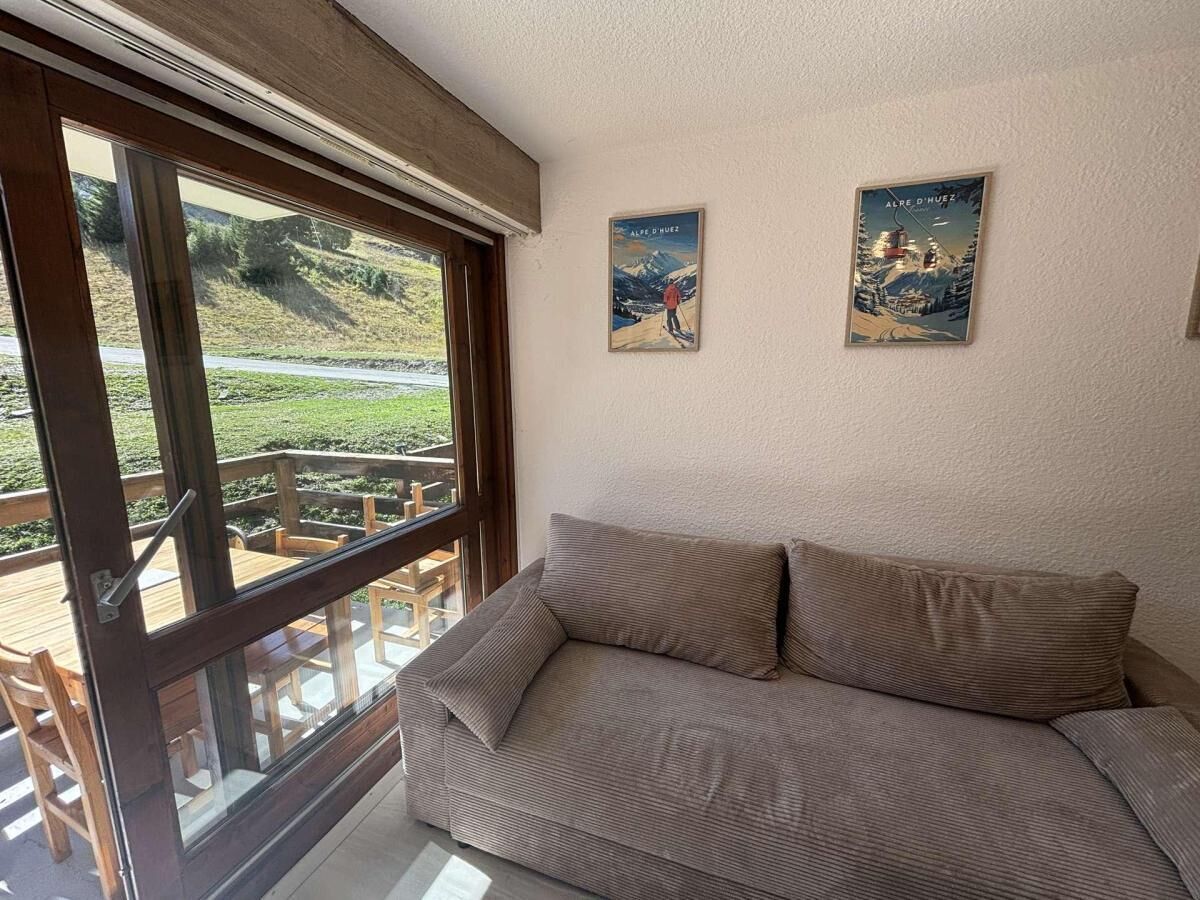 A room with a sofa, a window with a view of a mountain, and two posters on the wall.