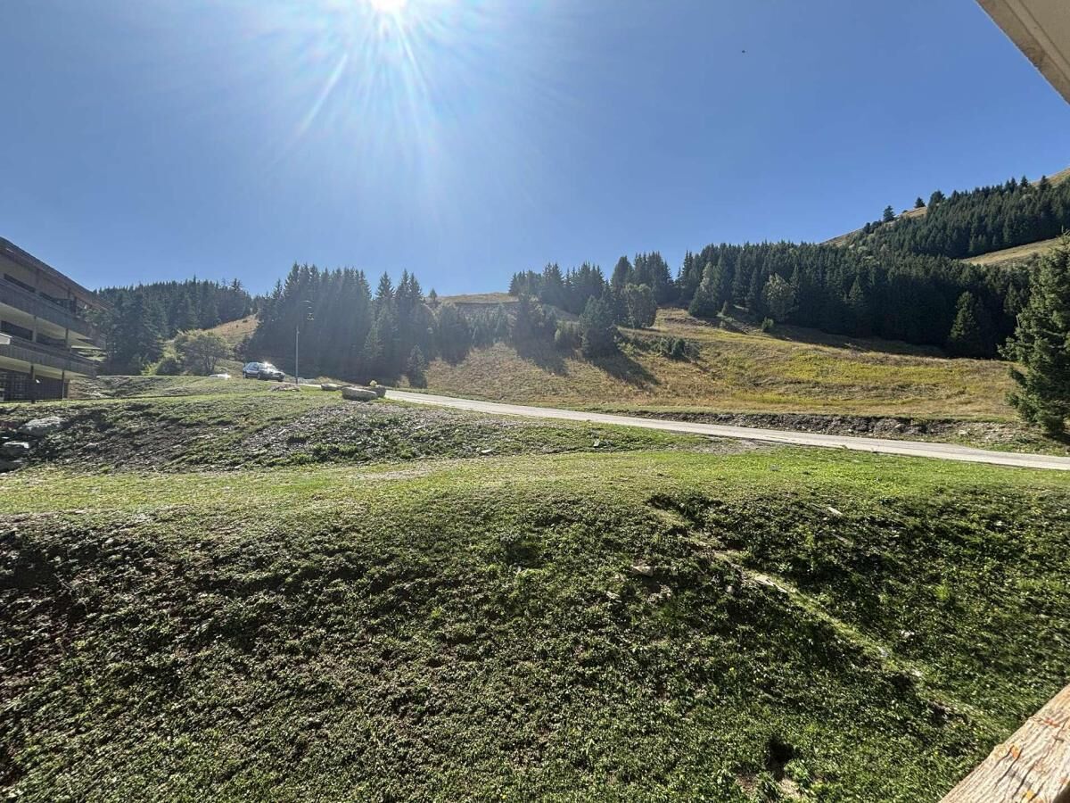 Un champ verdoyant avec une route et des bâtiments en arrière-plan.