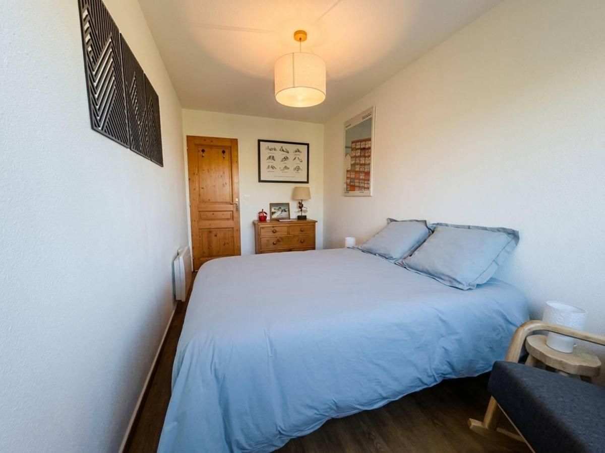 Une chambre à coucher comprenant un lit, une commode en bois, une table de chevet, une lampe et un élément de décoration murale.