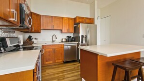 Eine moderne Küche mit Holzschränken, Edelstahlgeräten und einer weißen Arbeitsplatte.