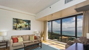 Ein großzügiges Wohnzimmer mit einem großen Fenster und Blick auf das Meer und die Stadt.
