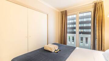 Een hotelkamer met een bed, een kledingkast, een raam met gordijnen en uitzicht op gebouwen.