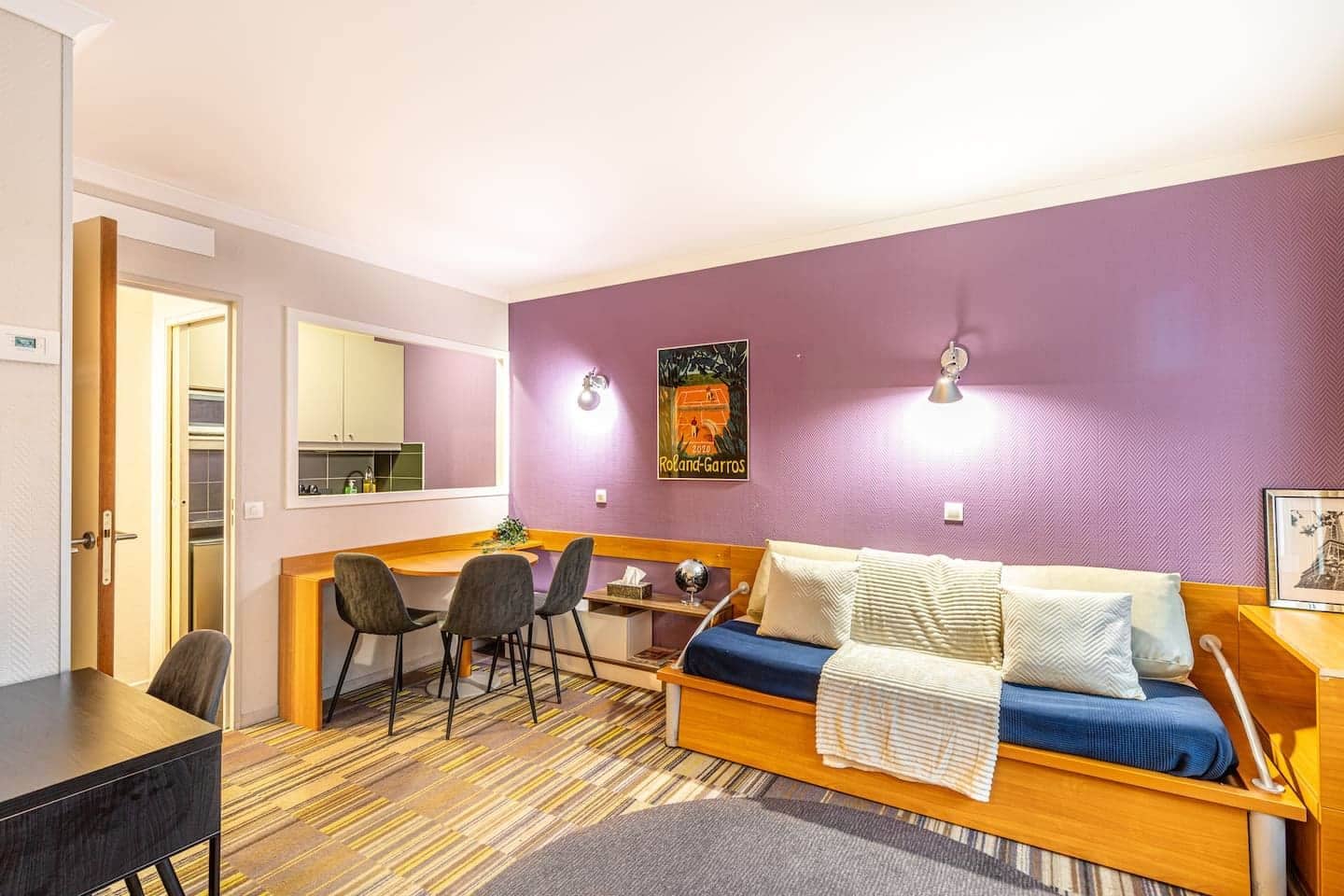 Un espacio habitable compacto con kitchenette, sofá cama y zona de comedor.