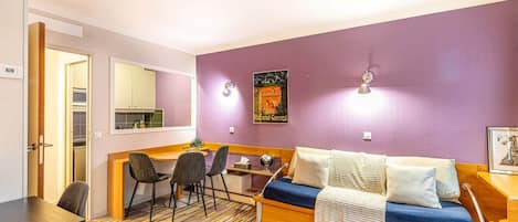 A compact living space with a kitchenette, a sofa bed, and a dining area.