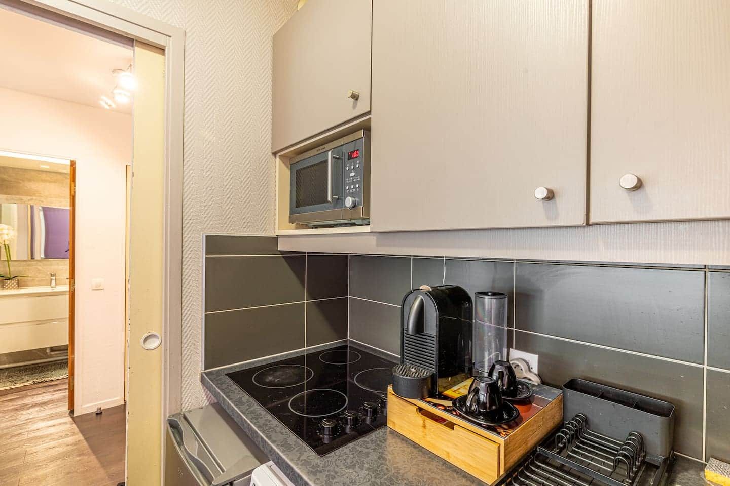 Een kleine keuken met een magnetron, kookplaat en koffiezetapparaat.