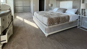 Ein Schlafzimmer mit einem großen Bett, einem Deckenventilator, einem Schminktisch und einem begehbaren Kleiderschrank.