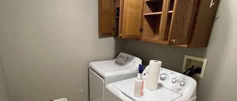 A laundry area with a washing machine, a dryer, and wooden cabinets above.