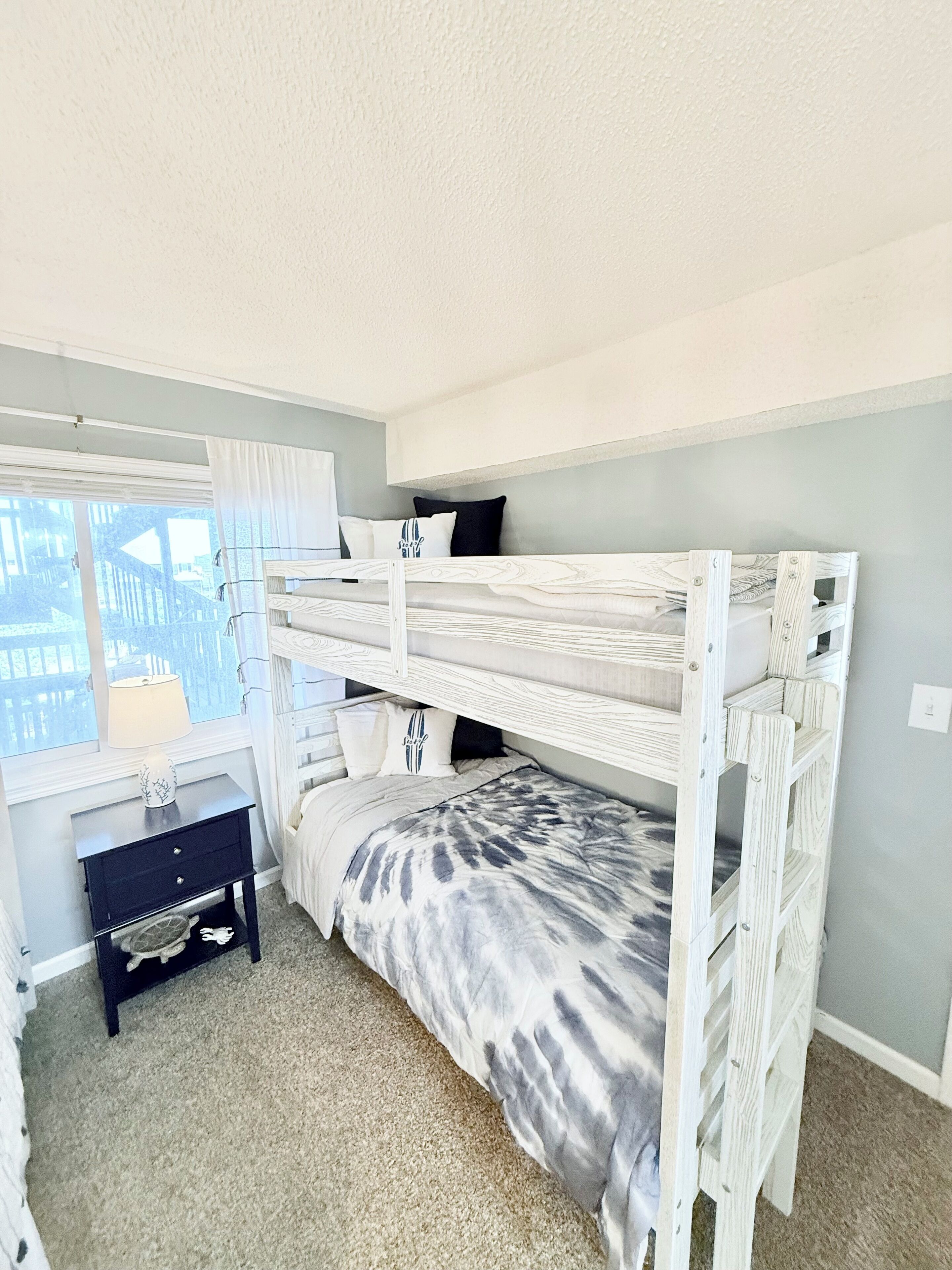 A bunk bed room with a desk and a window.